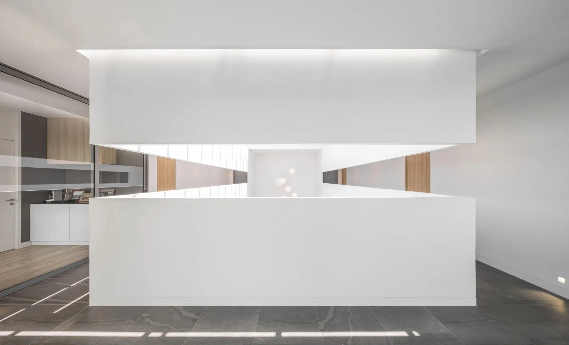Modern office space with minimalist design, white walls, wooden accents, and black tiled flooring.