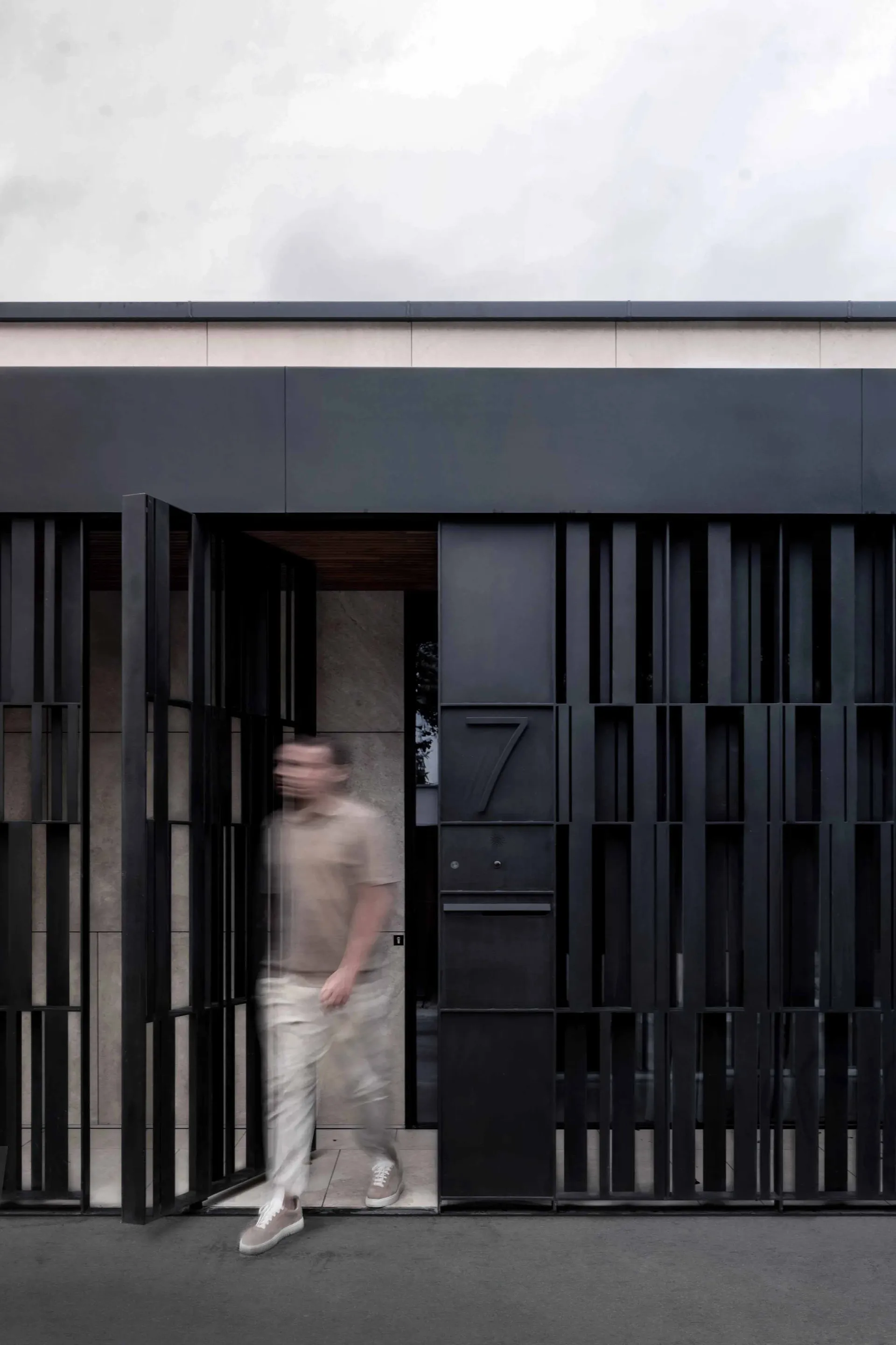 Modern building entrance with a metal door and black horizontal slats.