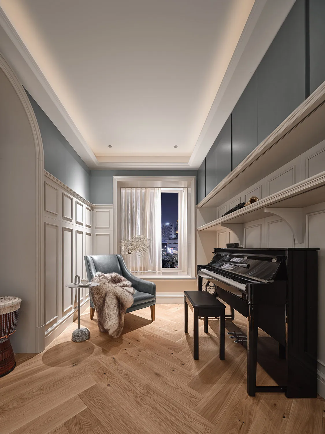 A modern living room with a wooden floor, featuring a comfortable armchair, a piano, and a serene atmosphere.