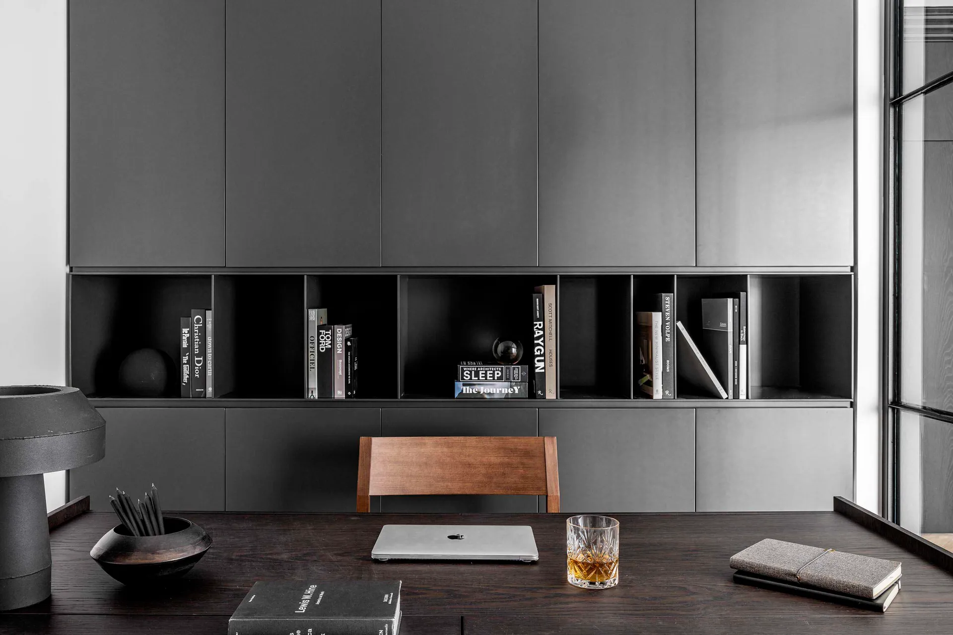 A modern office with black metal accents and grey wooden furniture.
