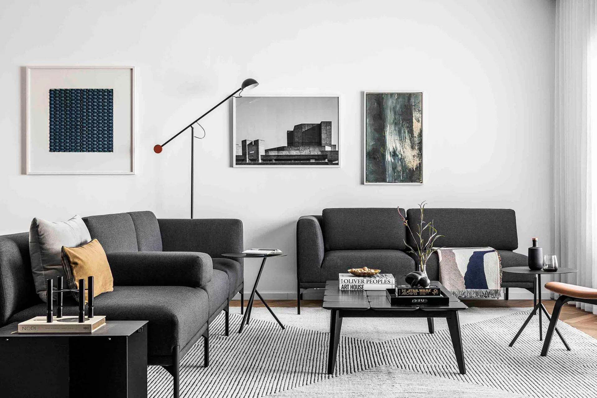 A modern living room featuring a white sofa and black coffee tables.