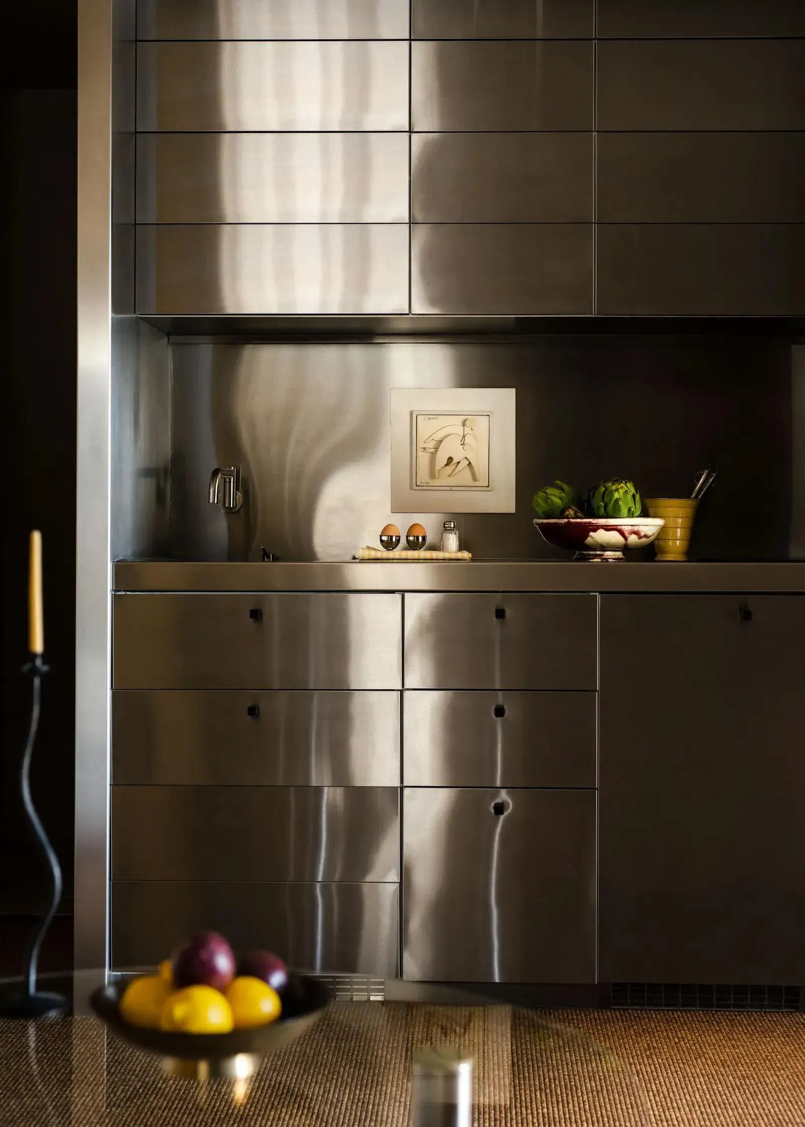 A modern minimalist kitchen with stainless steel cabinets and countertops, featuring a sleek and polished design.