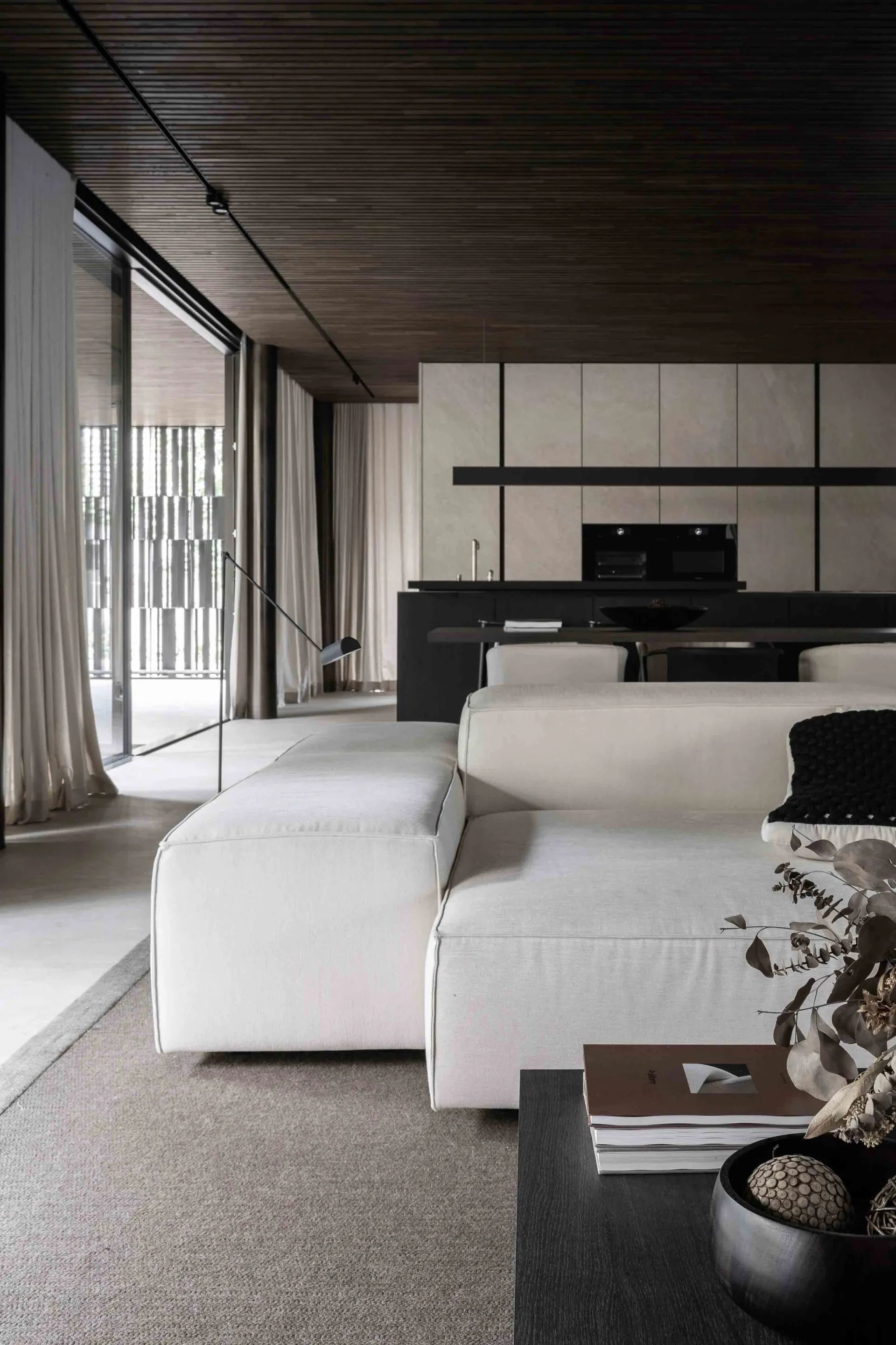 Modern minimalist living room featuring neutral textiles, concrete floor, and dark wood accents.