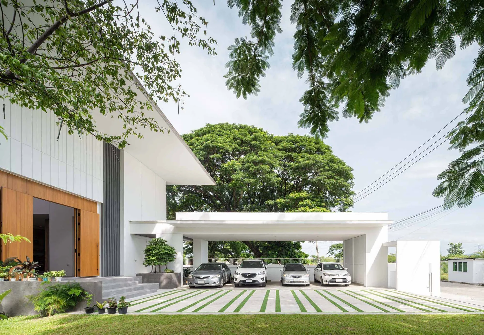 Modern carport with concrete flooring and vehicles parked underneath.
