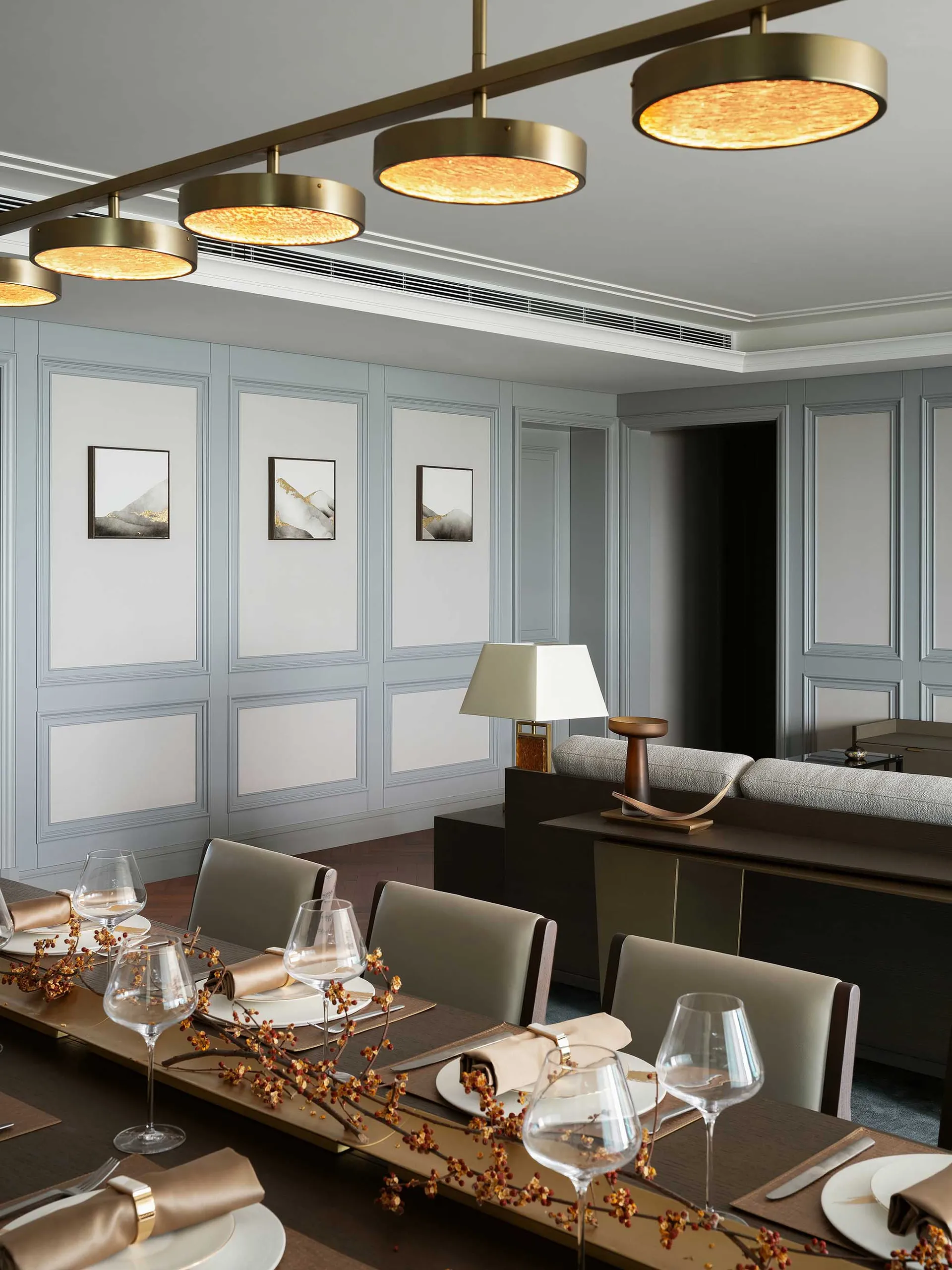 A modern dining room featuring metallic light fixtures and sleek furniture.