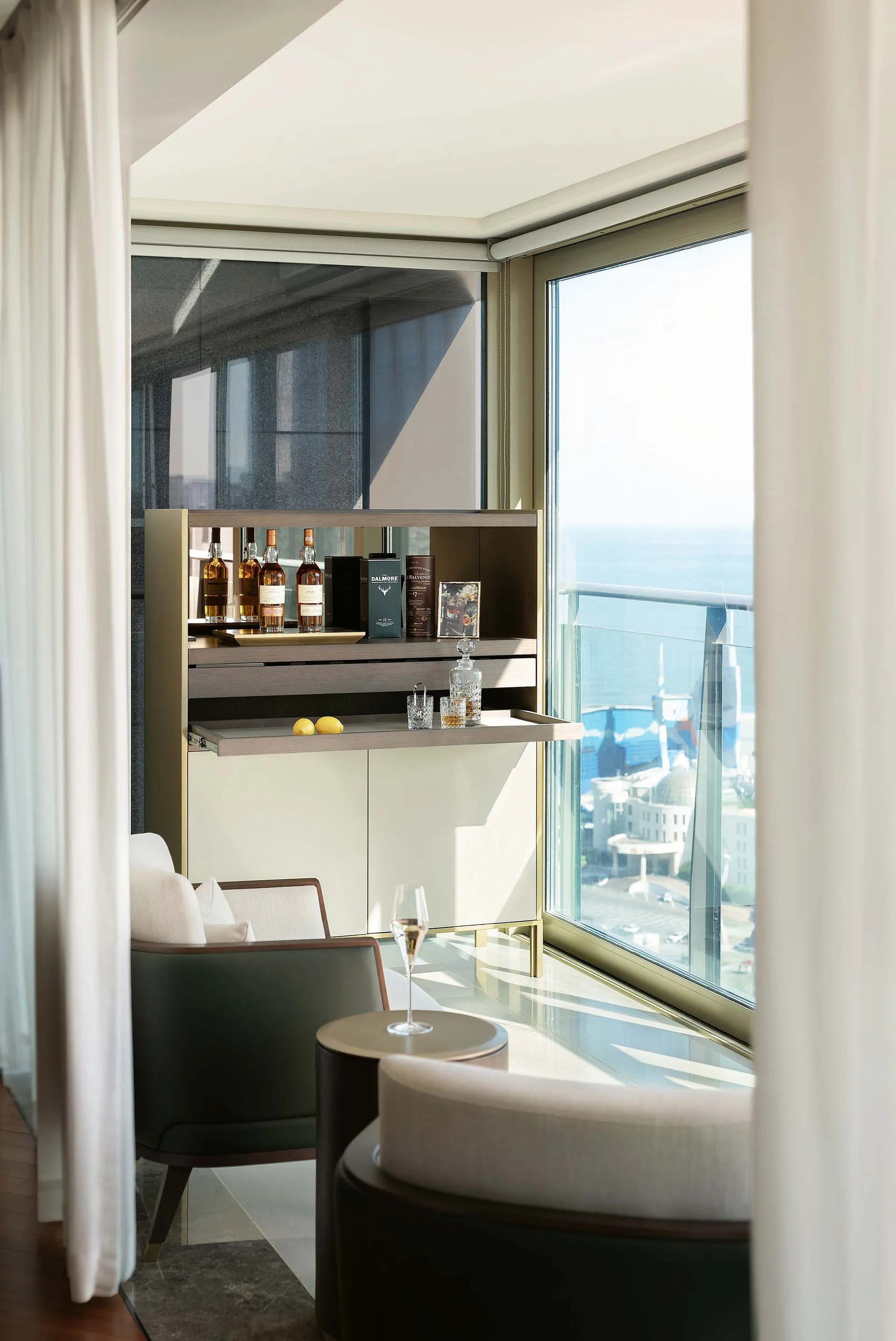 A modern living room with glass walls and a view of the city.
