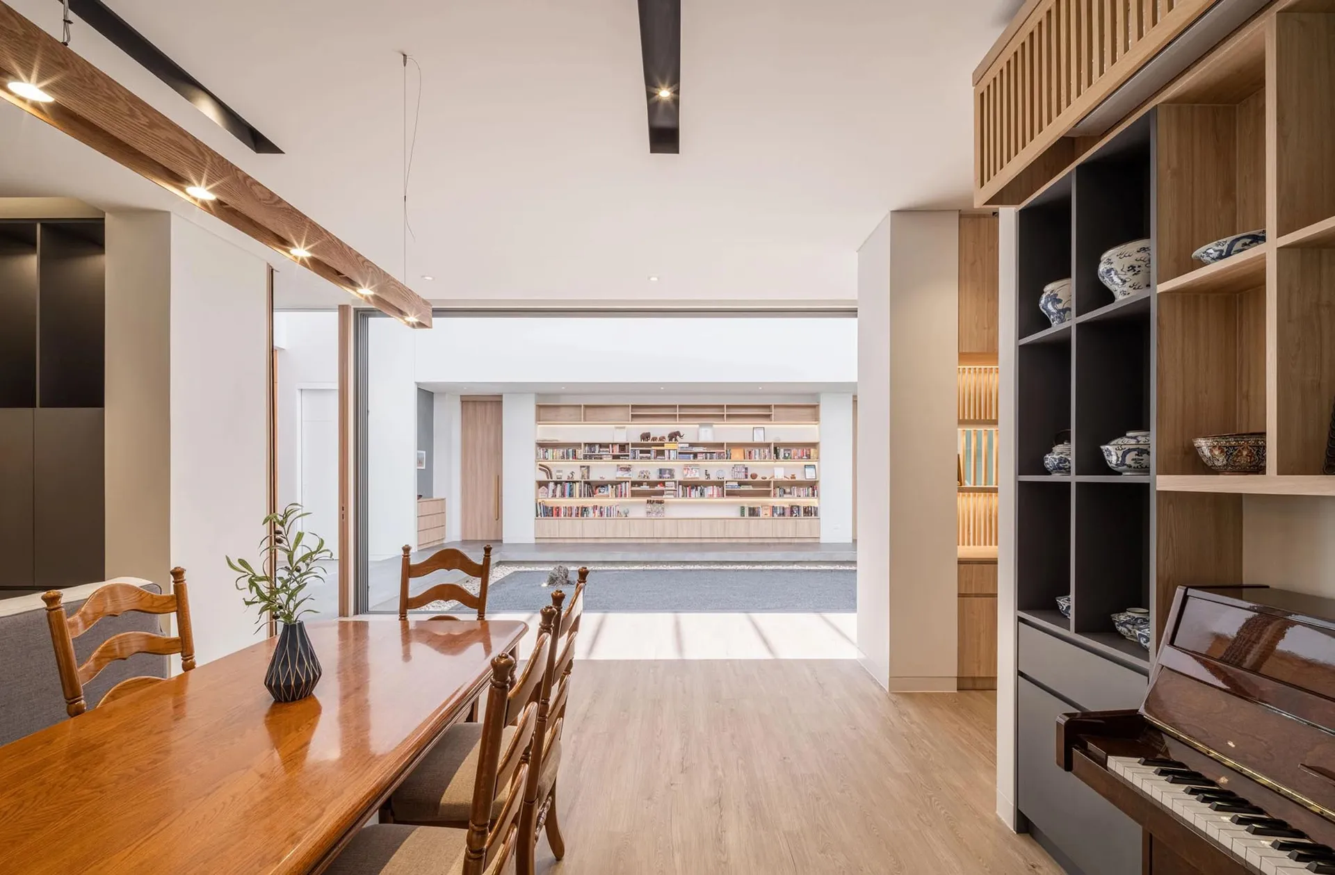 A modern living room and library space featuring wooden and glass materials.