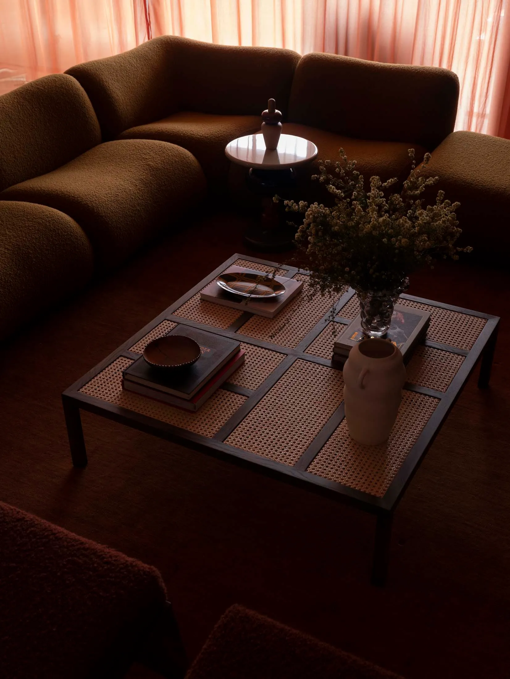 Modern industrial living room with brown couch, coffee table, and floral arrangement.