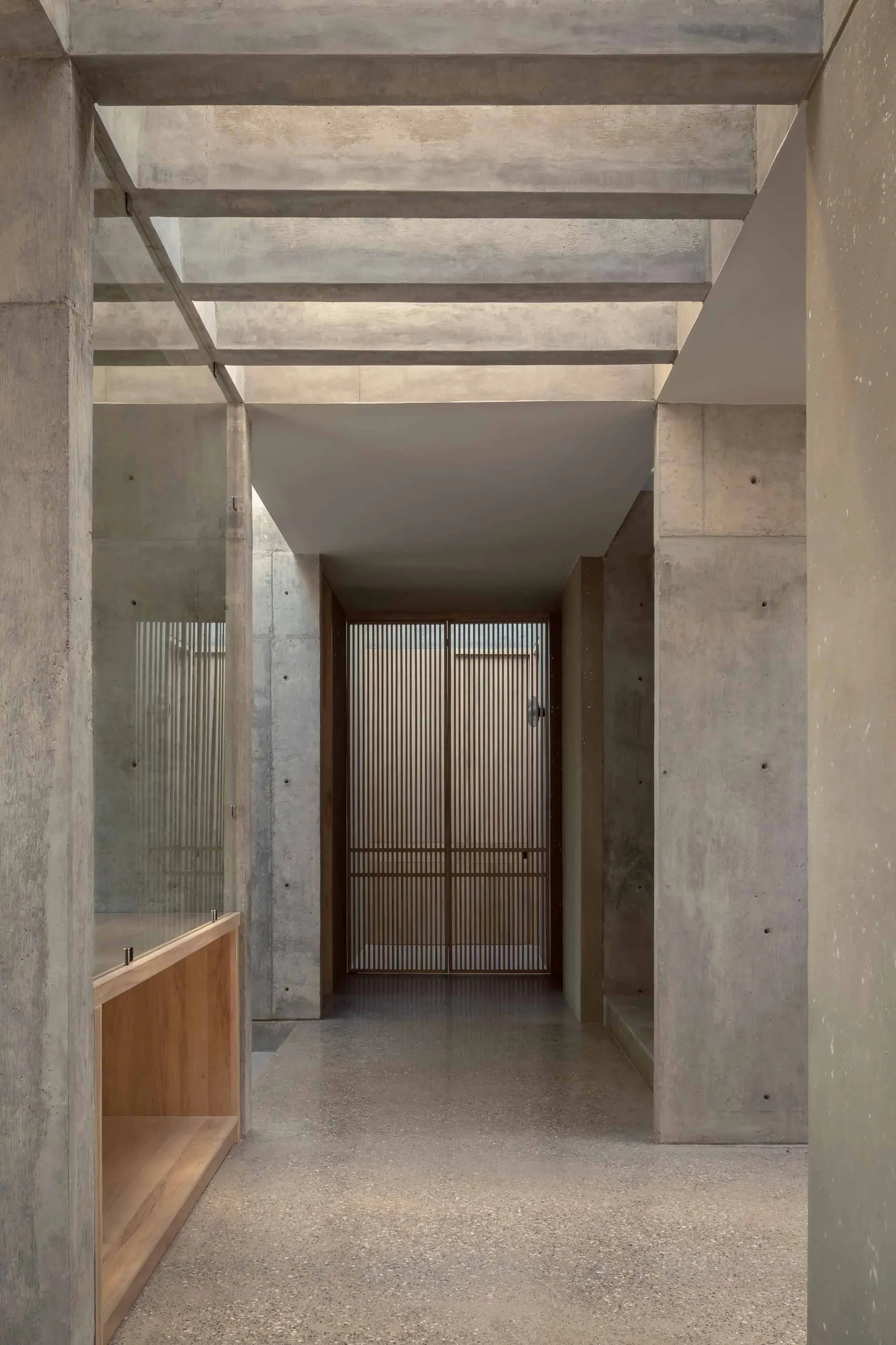 A minimalist interior design showcasing a concrete floor, glass walls, and wooden accents.