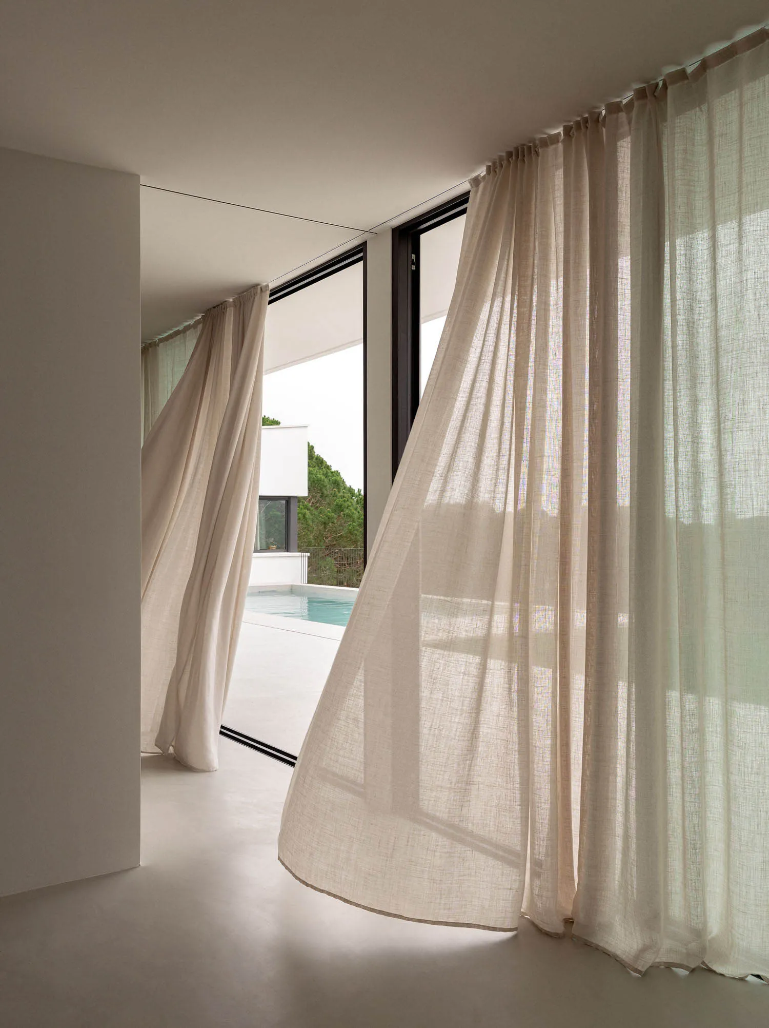 Minimalist residential interior with sheer curtains and concrete floor