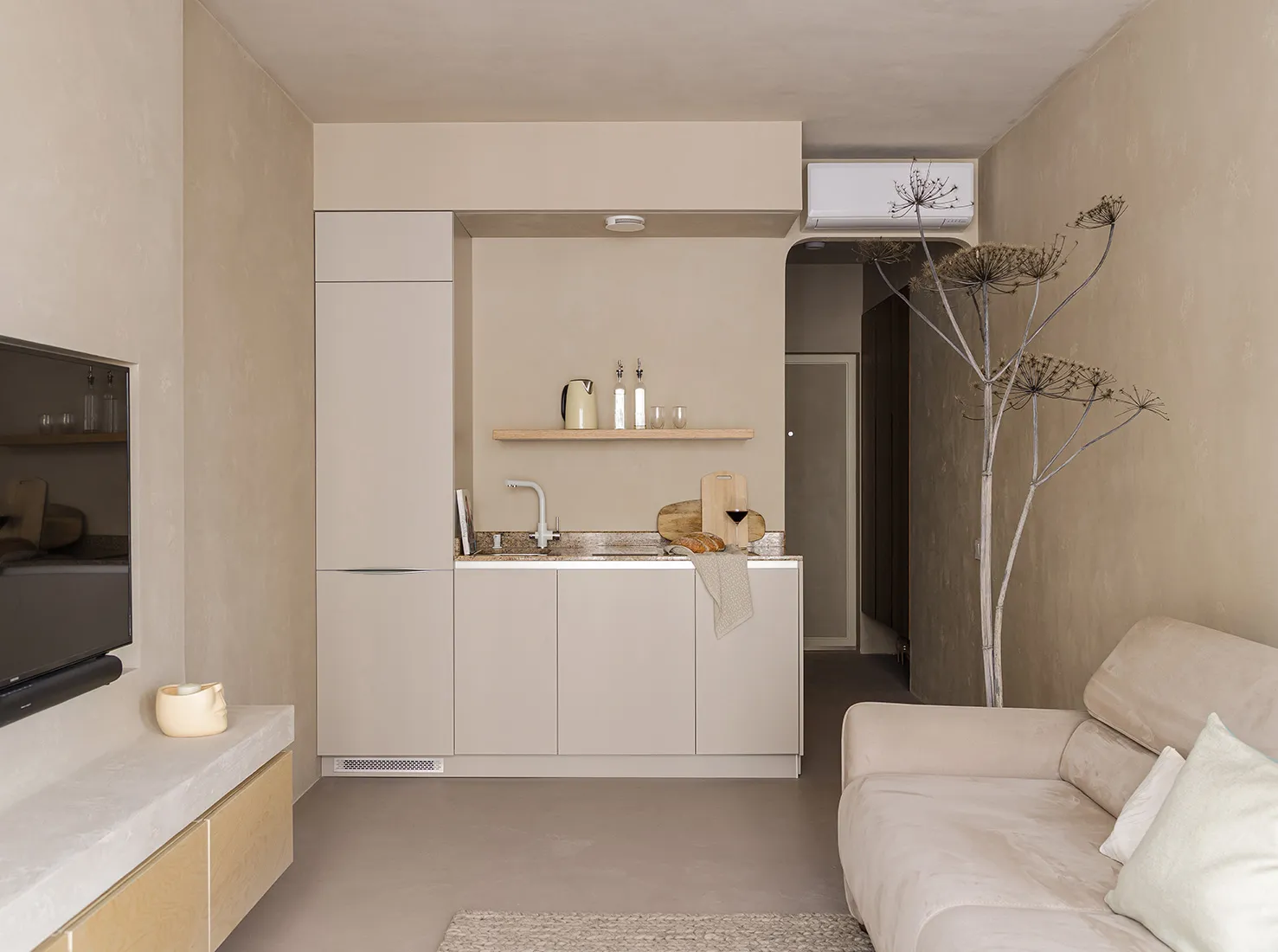 A minimalist residential kitchen featuring concrete countertops, wooden cabinets, and metal accents.