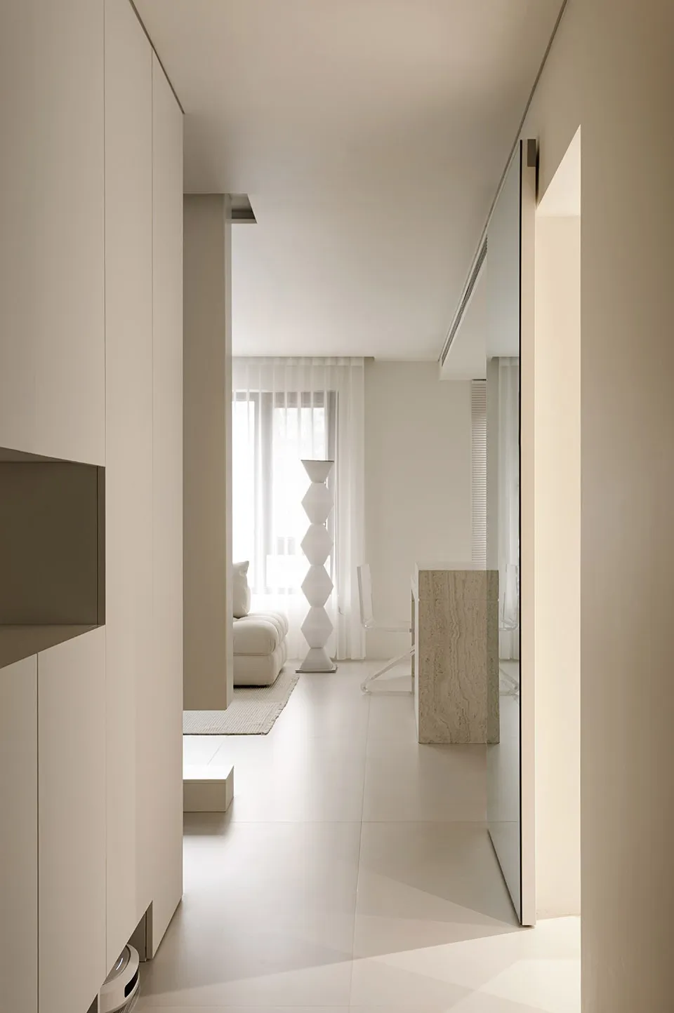 A minimalist white interior space with a light-colored geometric vase and a white sofa.