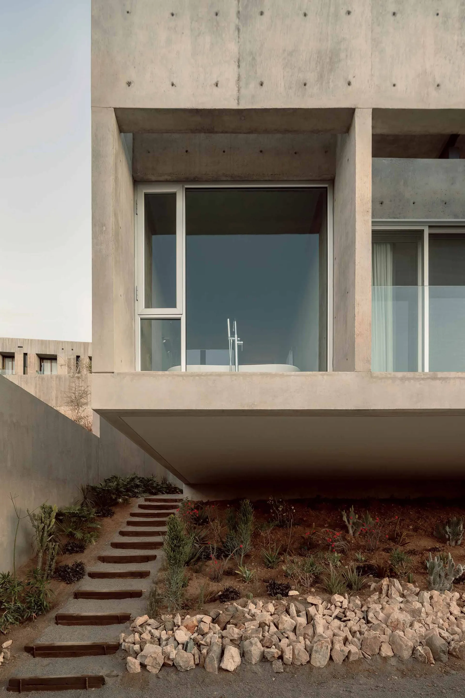 A modern home with a minimalist design featuring concrete and glass materials.