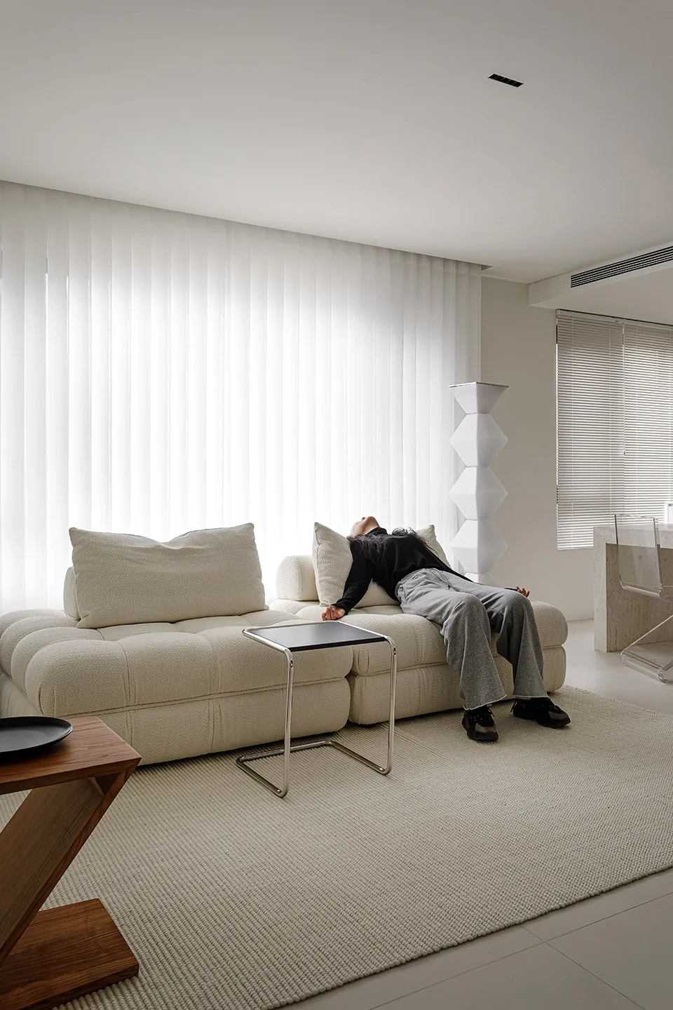 A modern living room with neutral-tones, featuring a comfortable seating area with a large, plush sofa, illuminated by soft, 