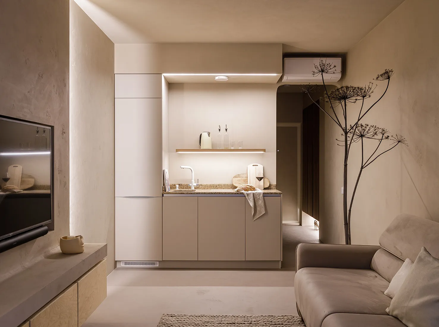 A minimalist residential kitchen with concrete walls and neutral color cabinets.