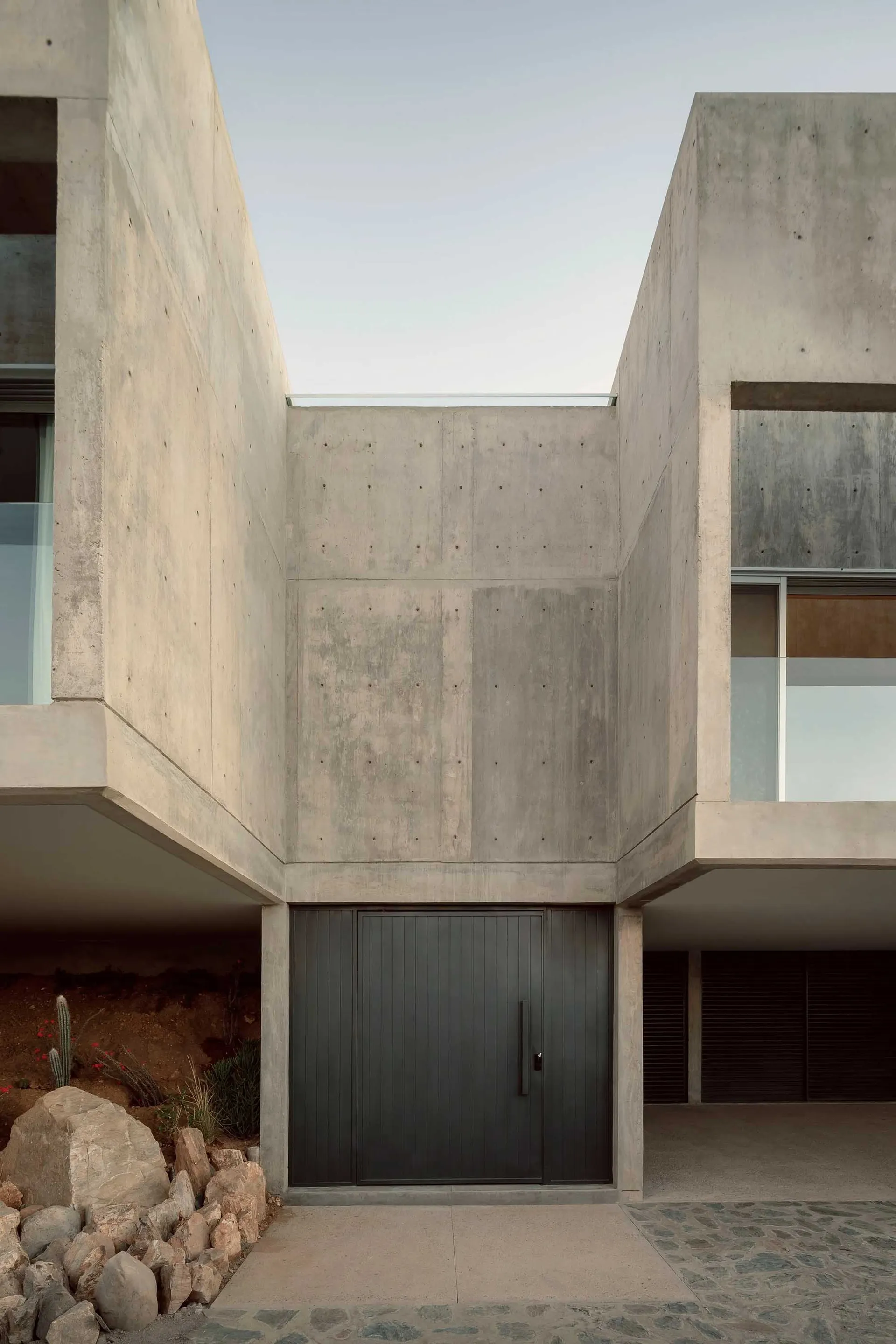 Modern house with concrete exterior and large glass windows.