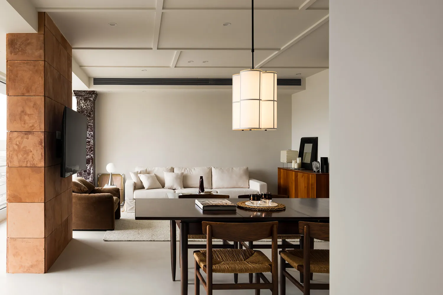 A modern minimalist living room featuring wooden furniture, white walls, and a white sofa with white cushions.