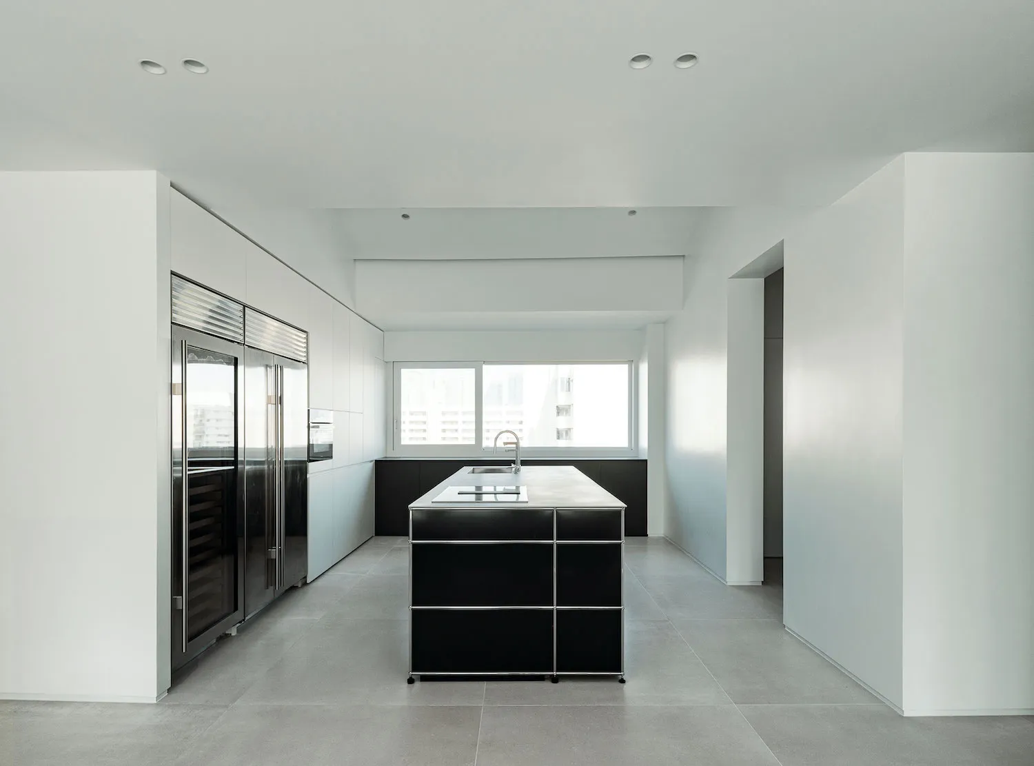 A modern kitchen with black metal cabinets and a concrete floor.