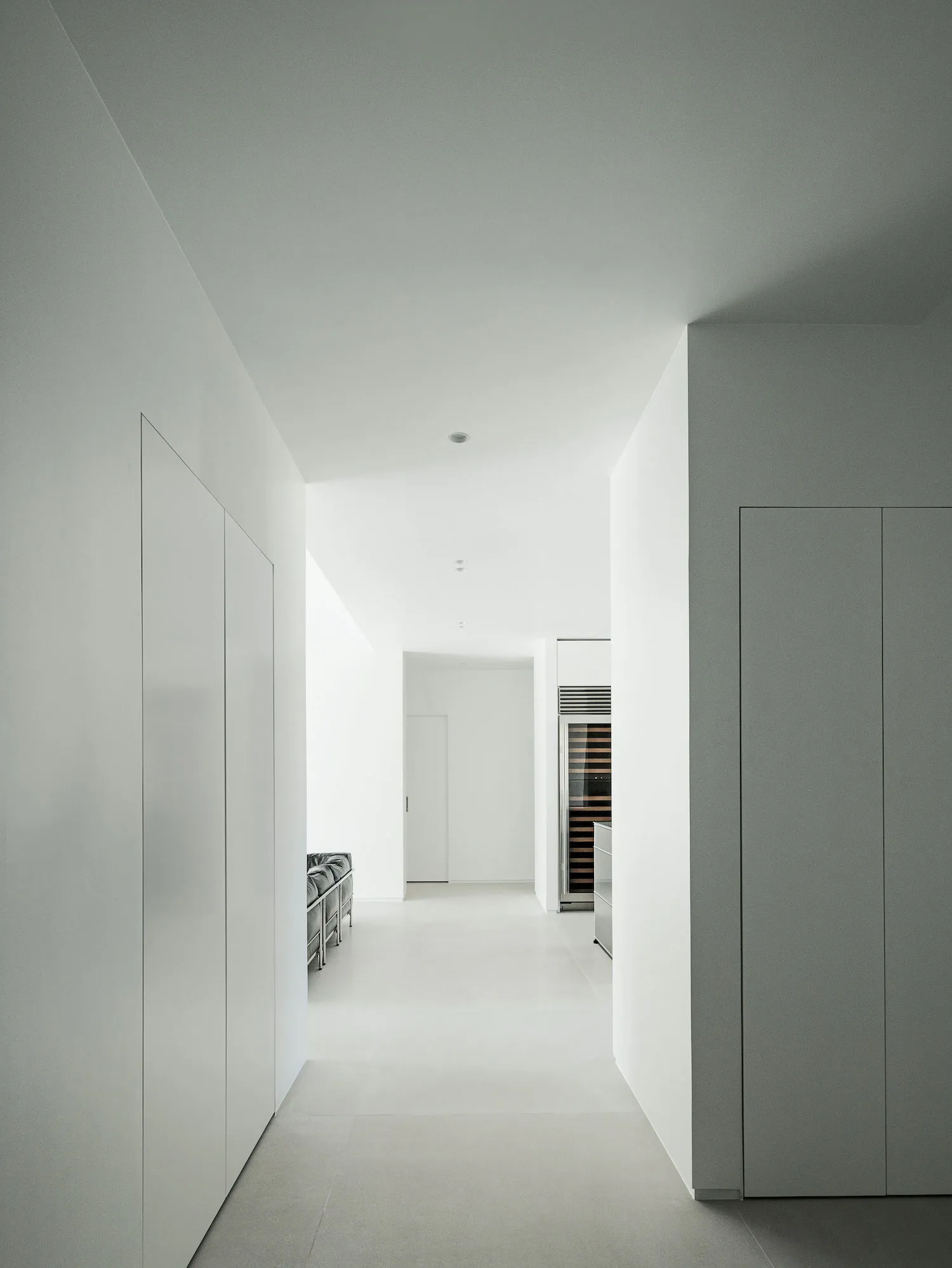 A minimalist apartment kitchen with concrete walls and floor.