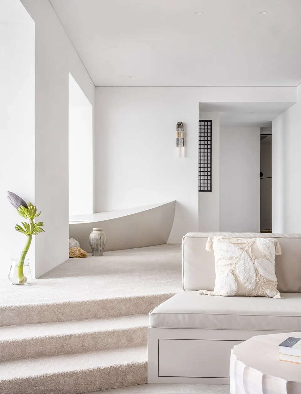 Minimalist living room featuring a modern cement sofa and a curved cement bathtub.