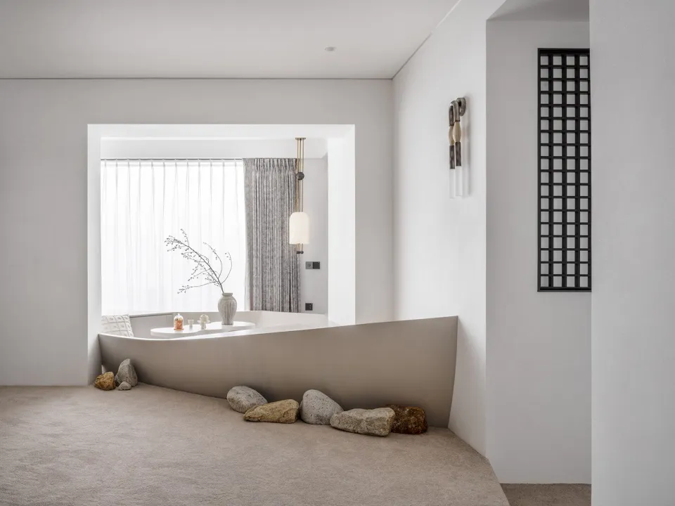 Minimalist living room with white walls, a sleek white bench, and natural stone accents.