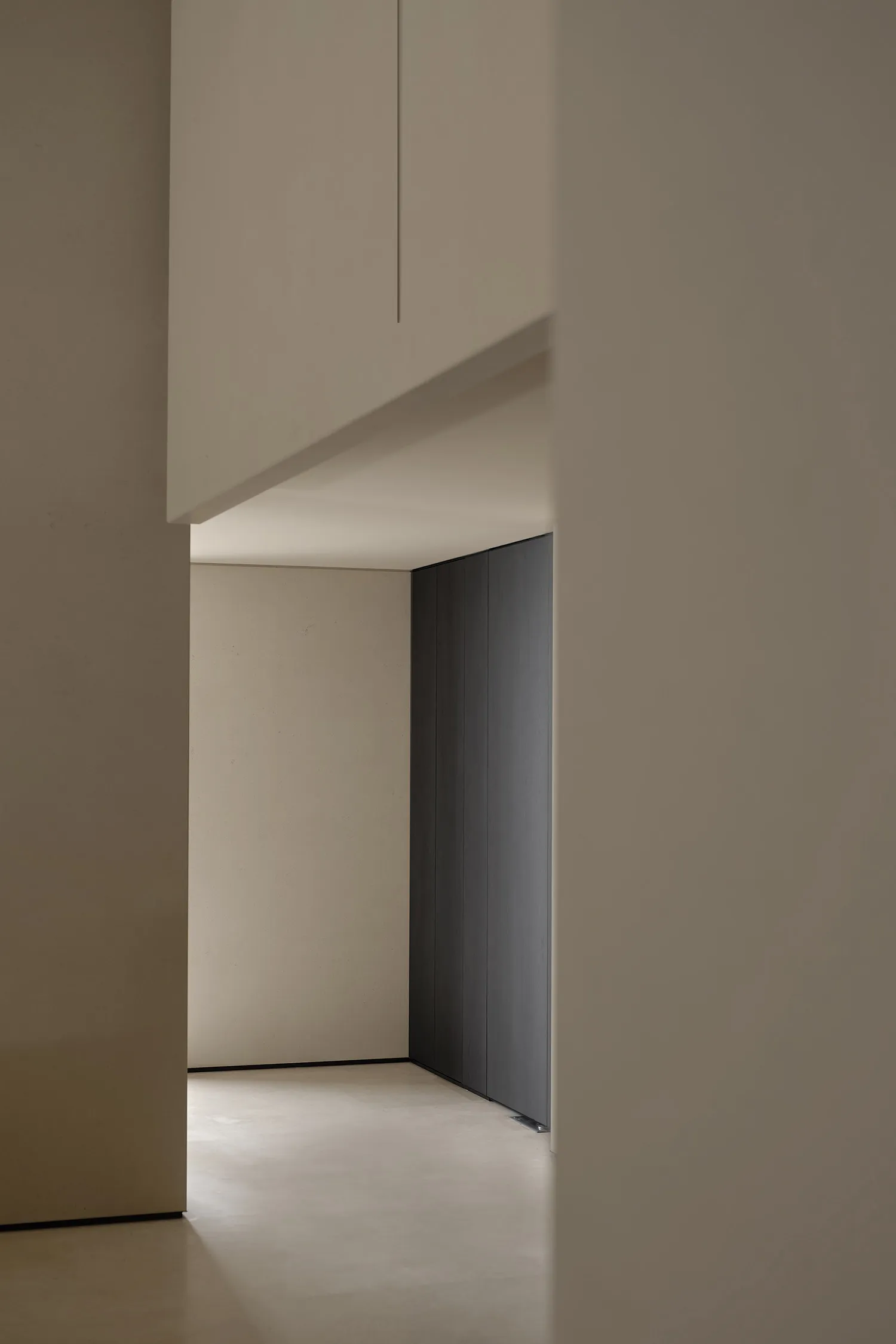 Modern residential interior with concrete walls and floor, minimal furniture.