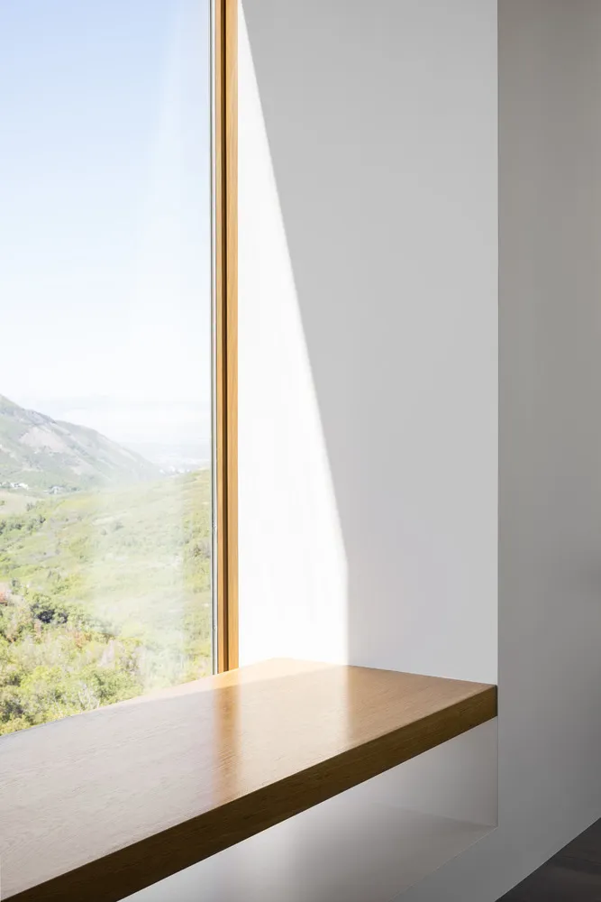 Modern interior design featuring a window seat with a white wall and a glass window overlooking a mountain view.