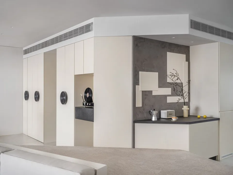 A minimalist kitchen with concrete walls and a black countertop.