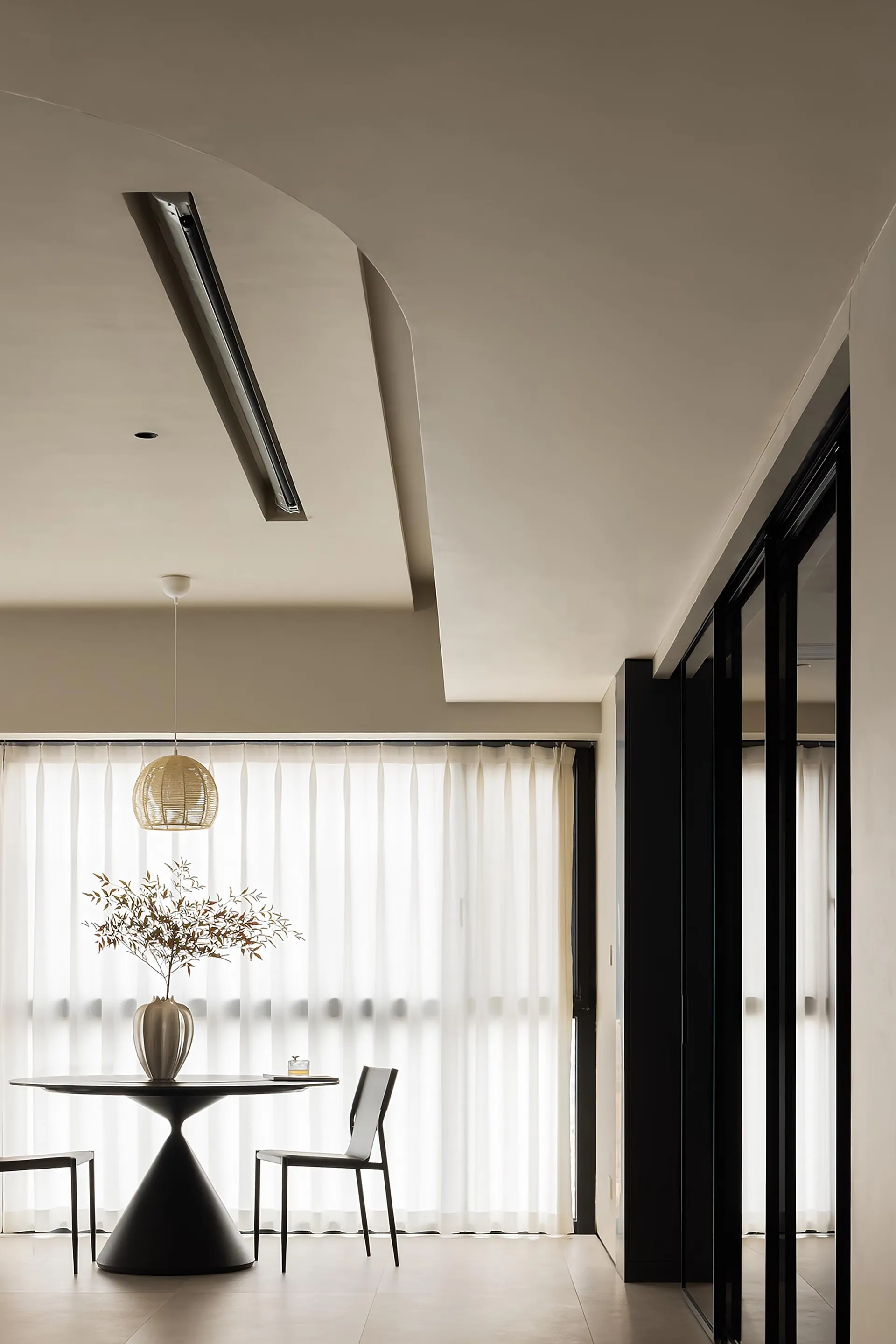 A minimalist modern residential living space featuring transparent textiles and dark wooden accents.