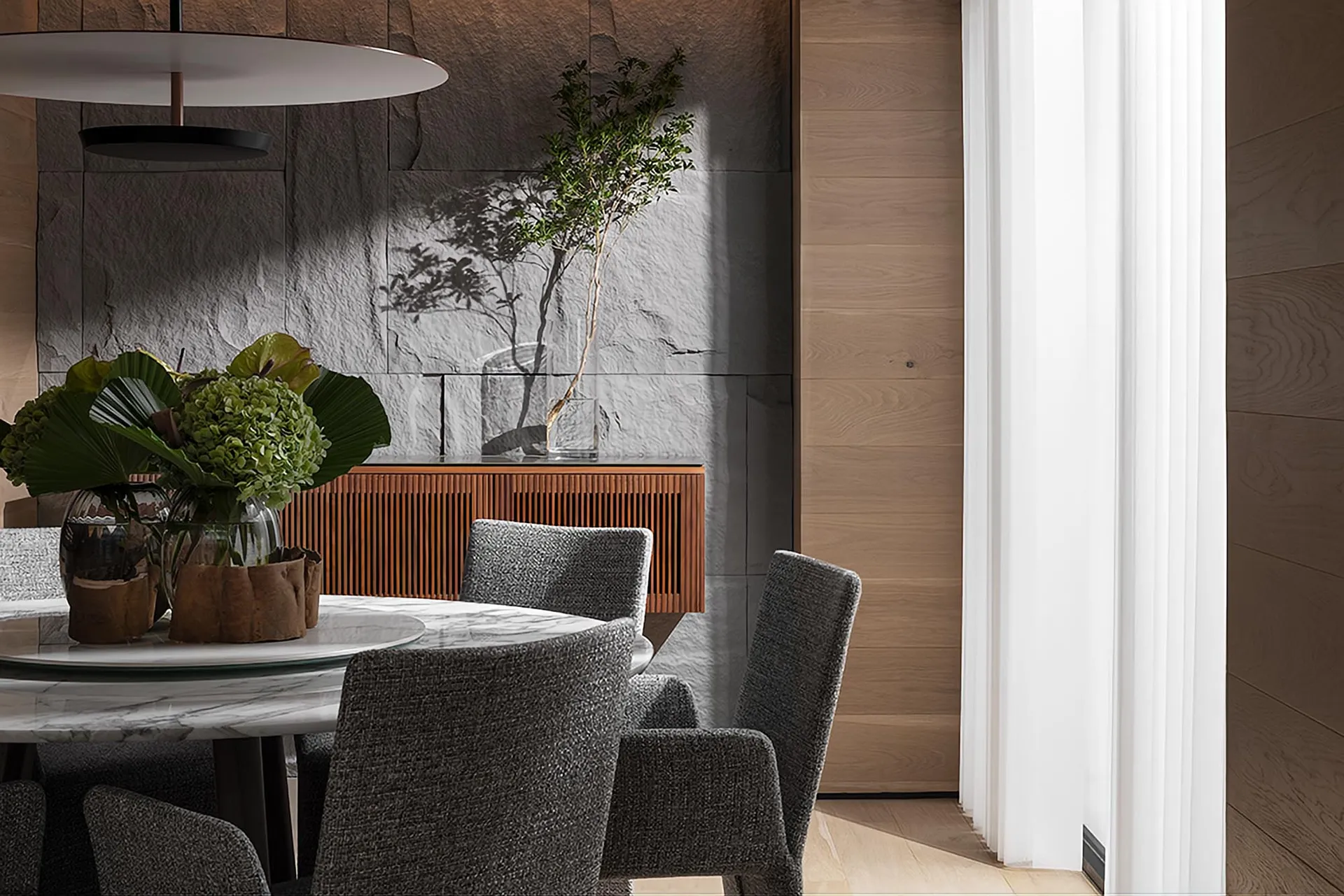 Modern dining room featuring a table with glass and marble elements, surrounded by upholstered chairs and a wall made of glas