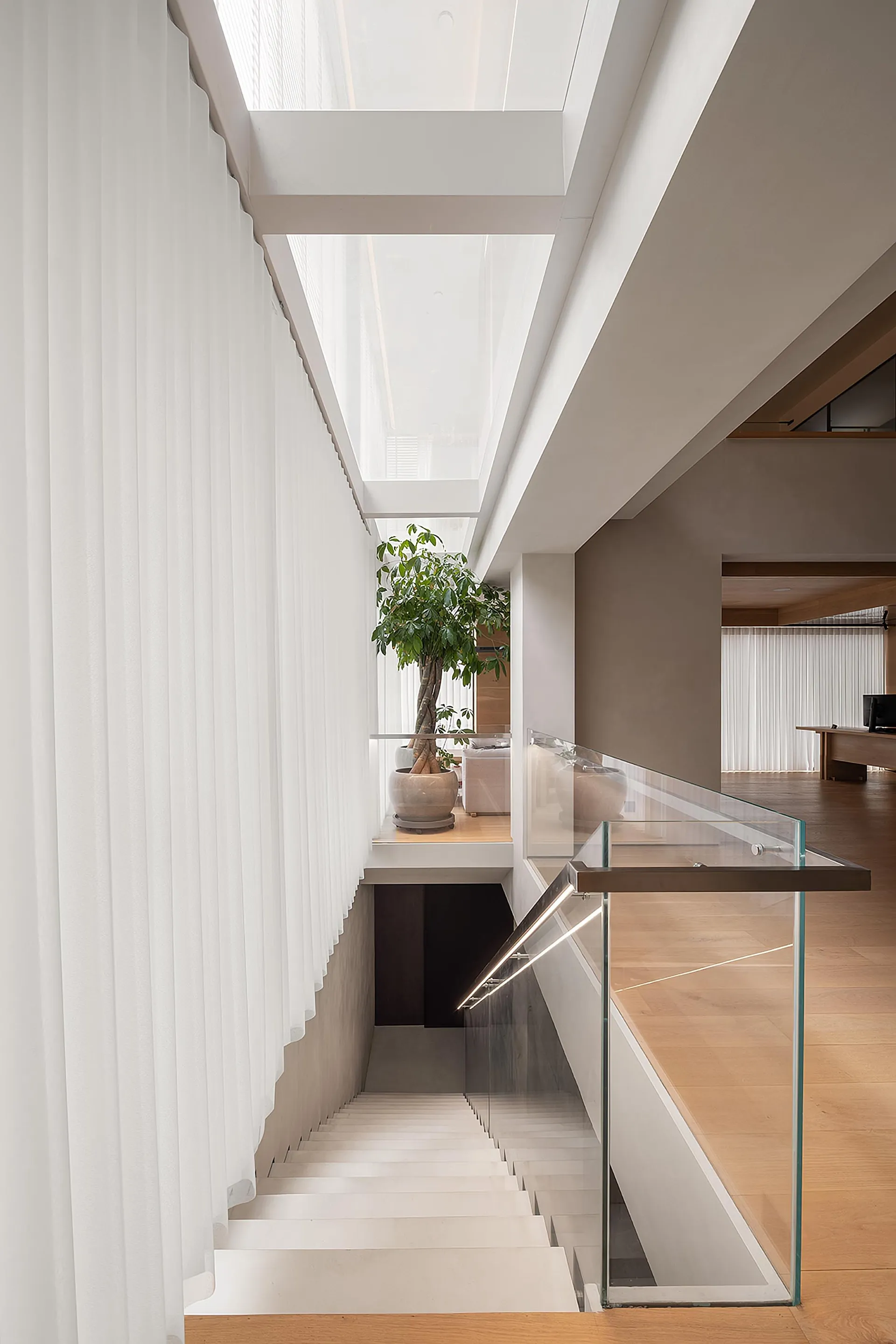 Modern staircase featuring glass railings, concrete steps, and timber accents.