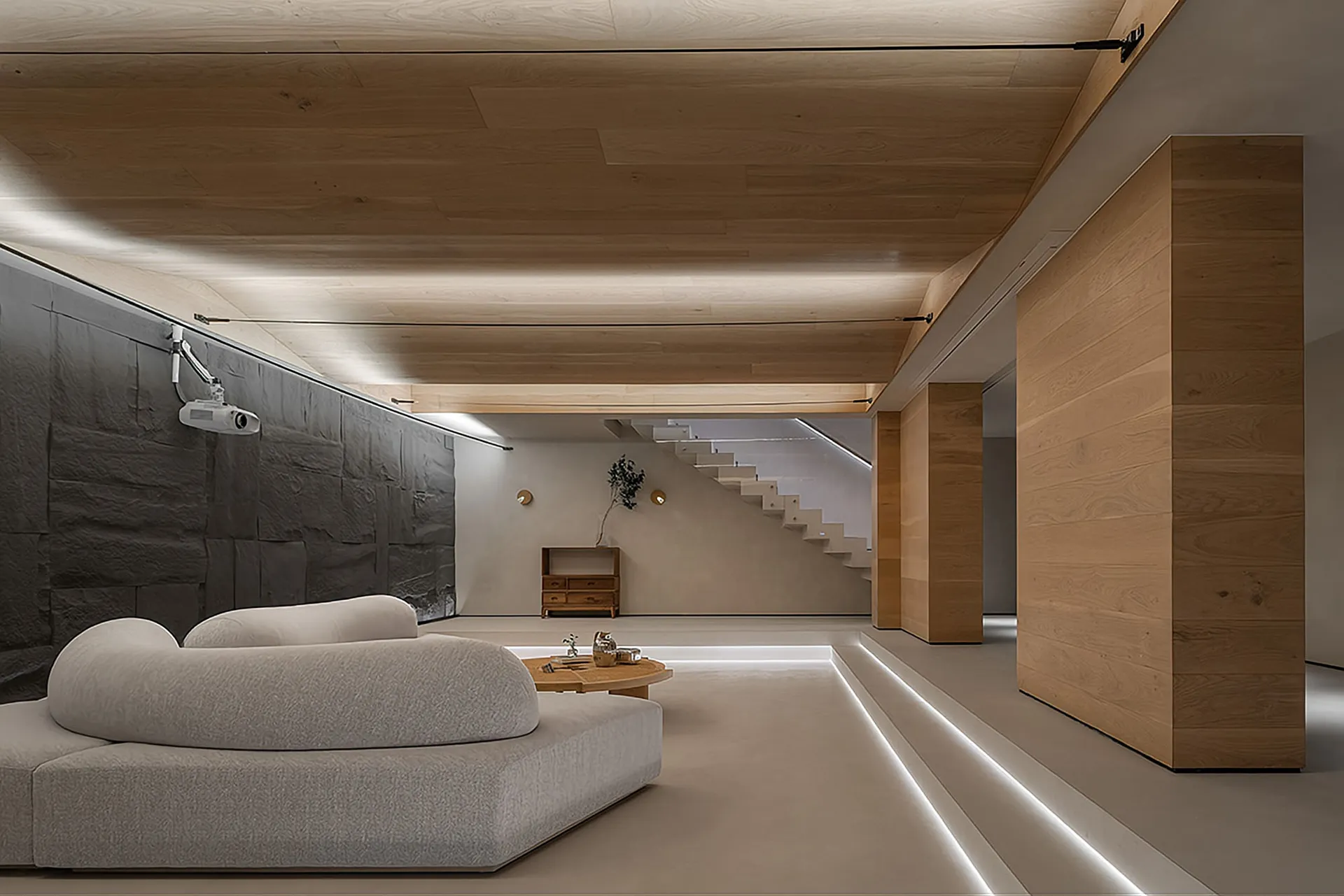 A modern minimalist living room with a white sofa, a round wooden coffee table, and a projector setup on a black, stone-like 