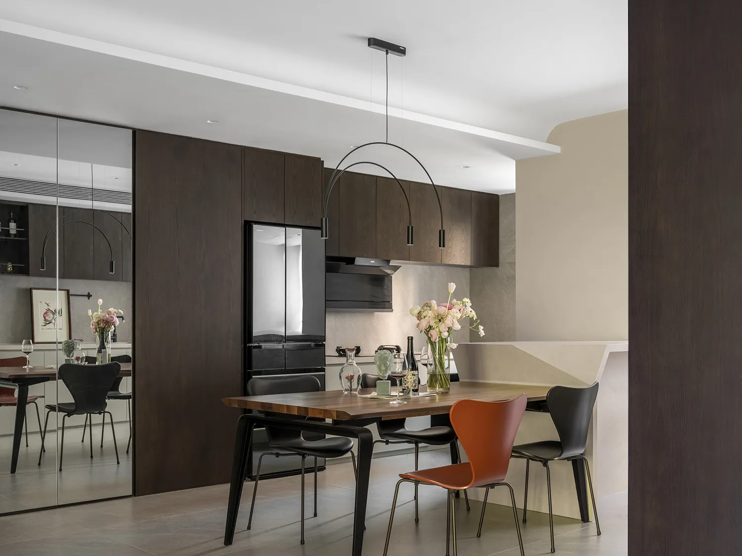 A modern kitchen with wooden furniture mix, featuring a dining table, chairs, and a refrigerator.