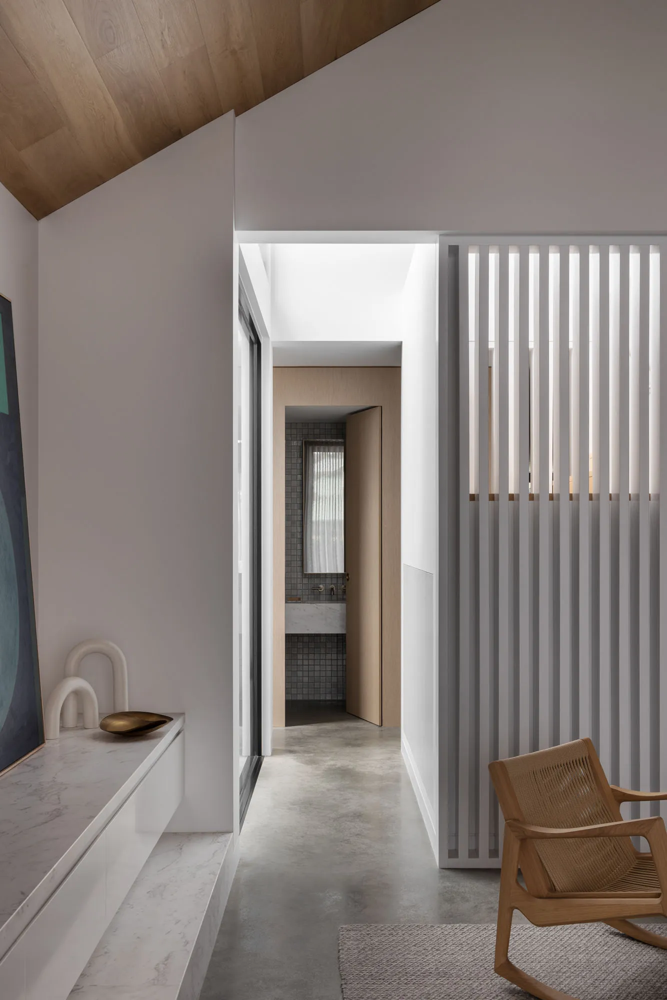 A modern minimalist entrance featuring concrete flooring and wooden accents.