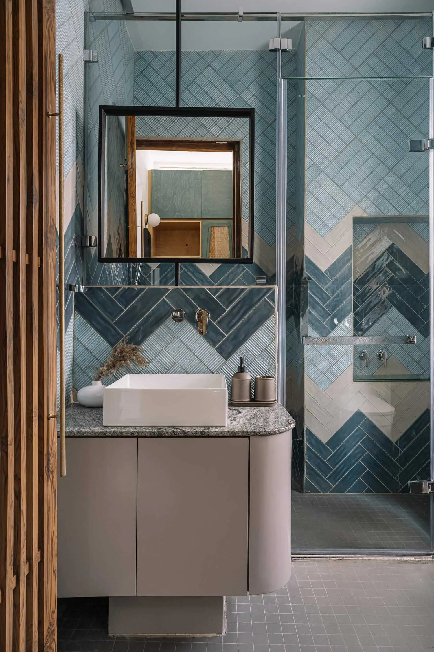 Modern bathroom interior featuring a blue tile pattern wall and a white sink on a grey countertop.