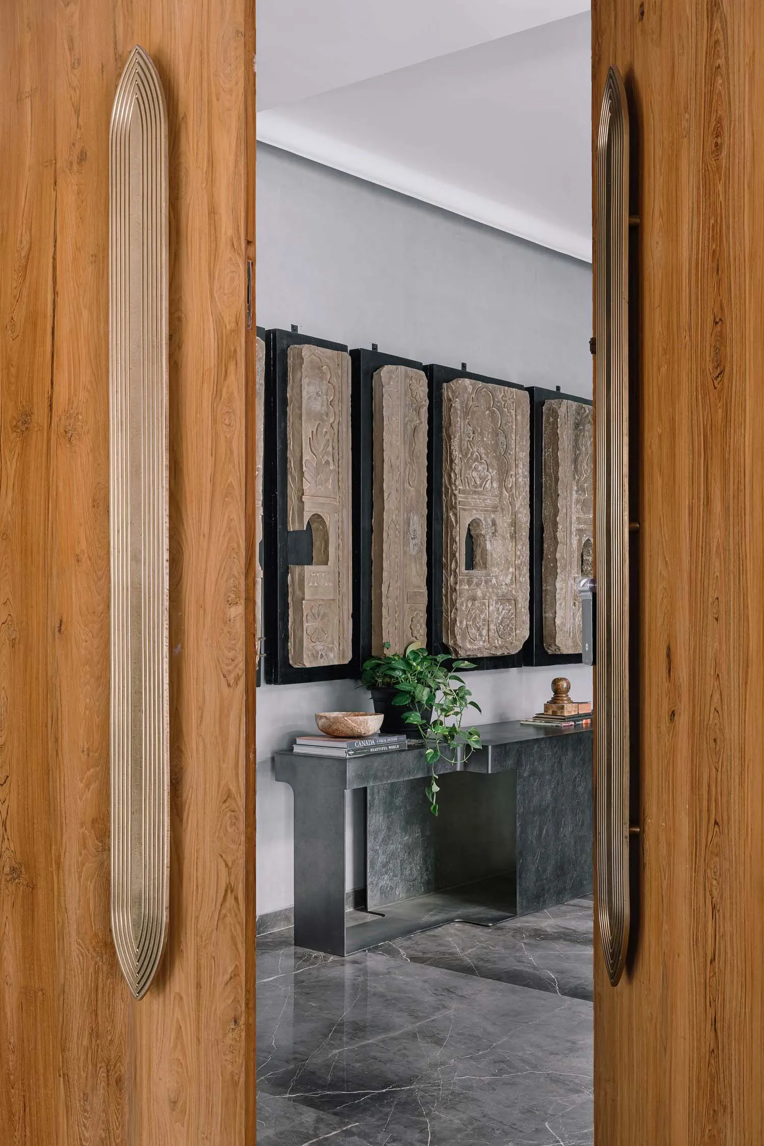 Entrance hall featuring modern design with wooden doors, concrete flooring, and carved stone panels.