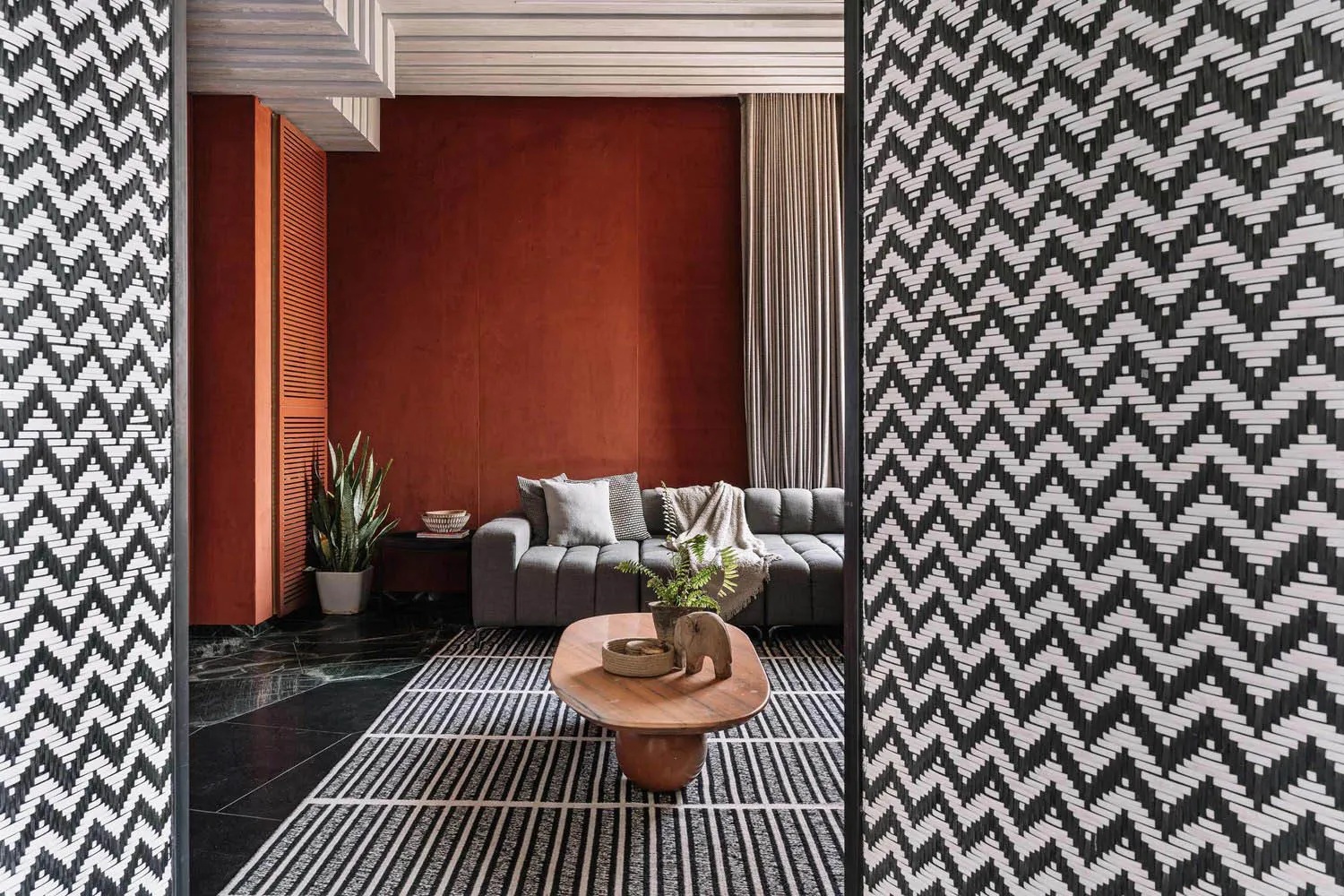 A stylish modern living room with textured wallpaper, a dark wood coffee table, and a comfortable grey sofa.