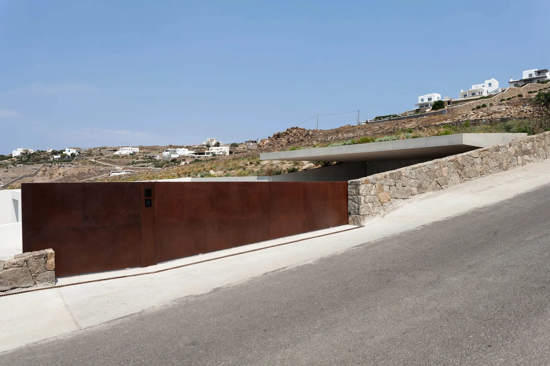 Modern residential entrance featuring a steel gate with a concrete ledge.