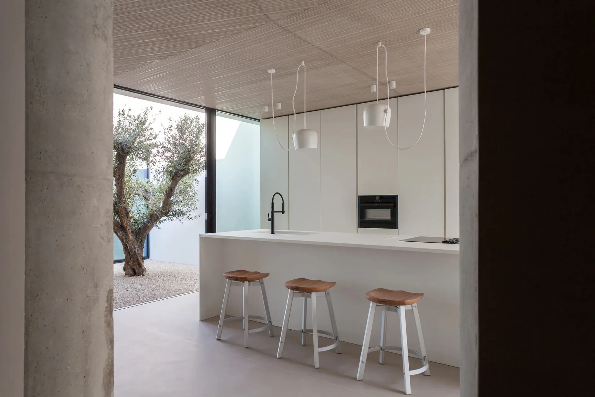 A modern kitchen with white pendant lights, white cabinets, and a white countertop.