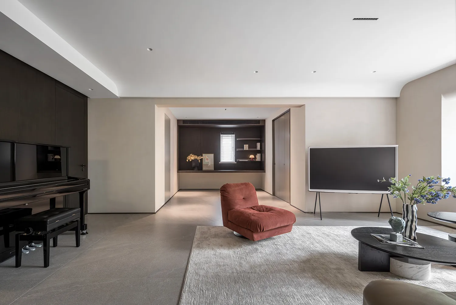 A modern living room with concrete flooring, minimalist decor, and a single red plush chair.