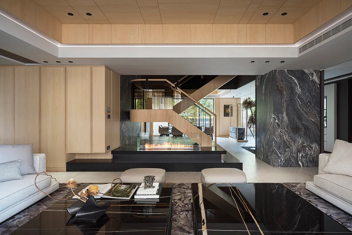 A modern living room featuring a marble floor and black glass coffee table.