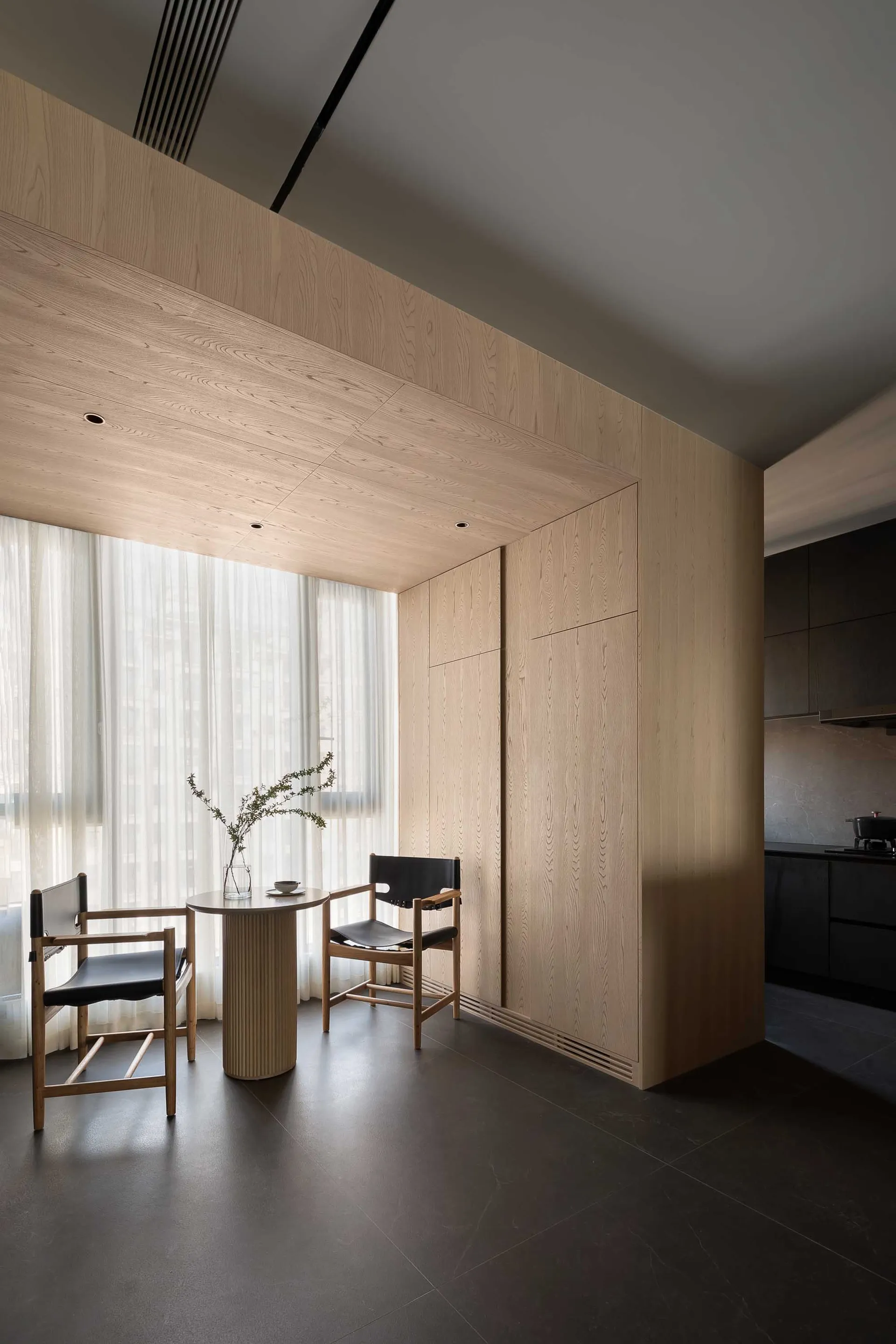 A minimalist residential dining area with wood walls and floor.