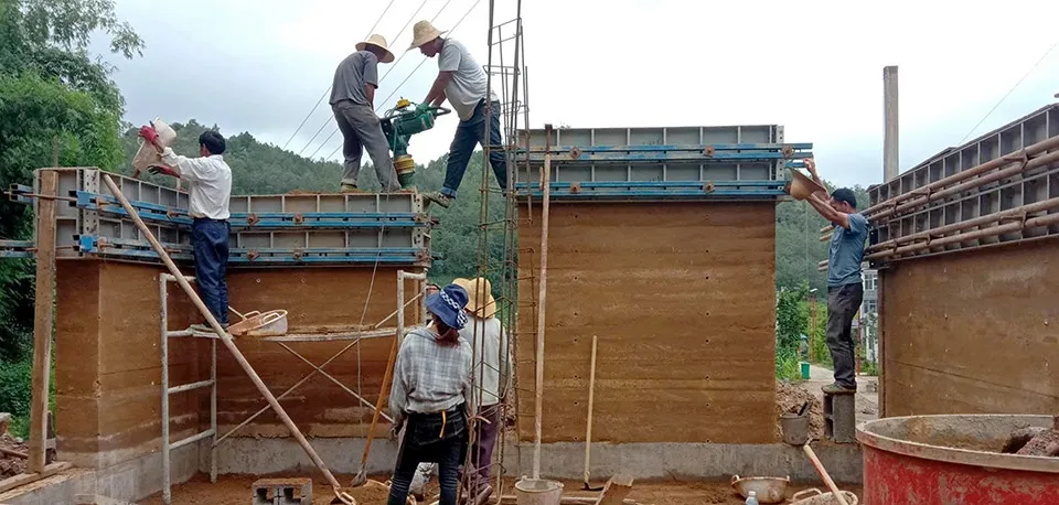 工人在工地使用混凝土磚塊與鷹架建造牆面。