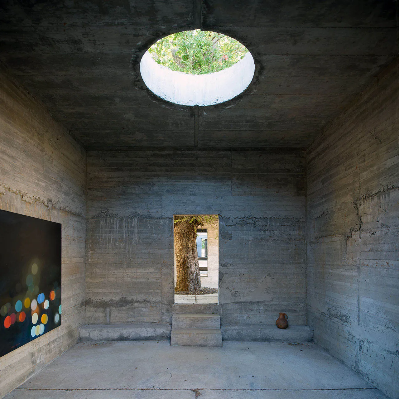 Concrete walls and ceiling with a circular window in a minimalist interior design setting.