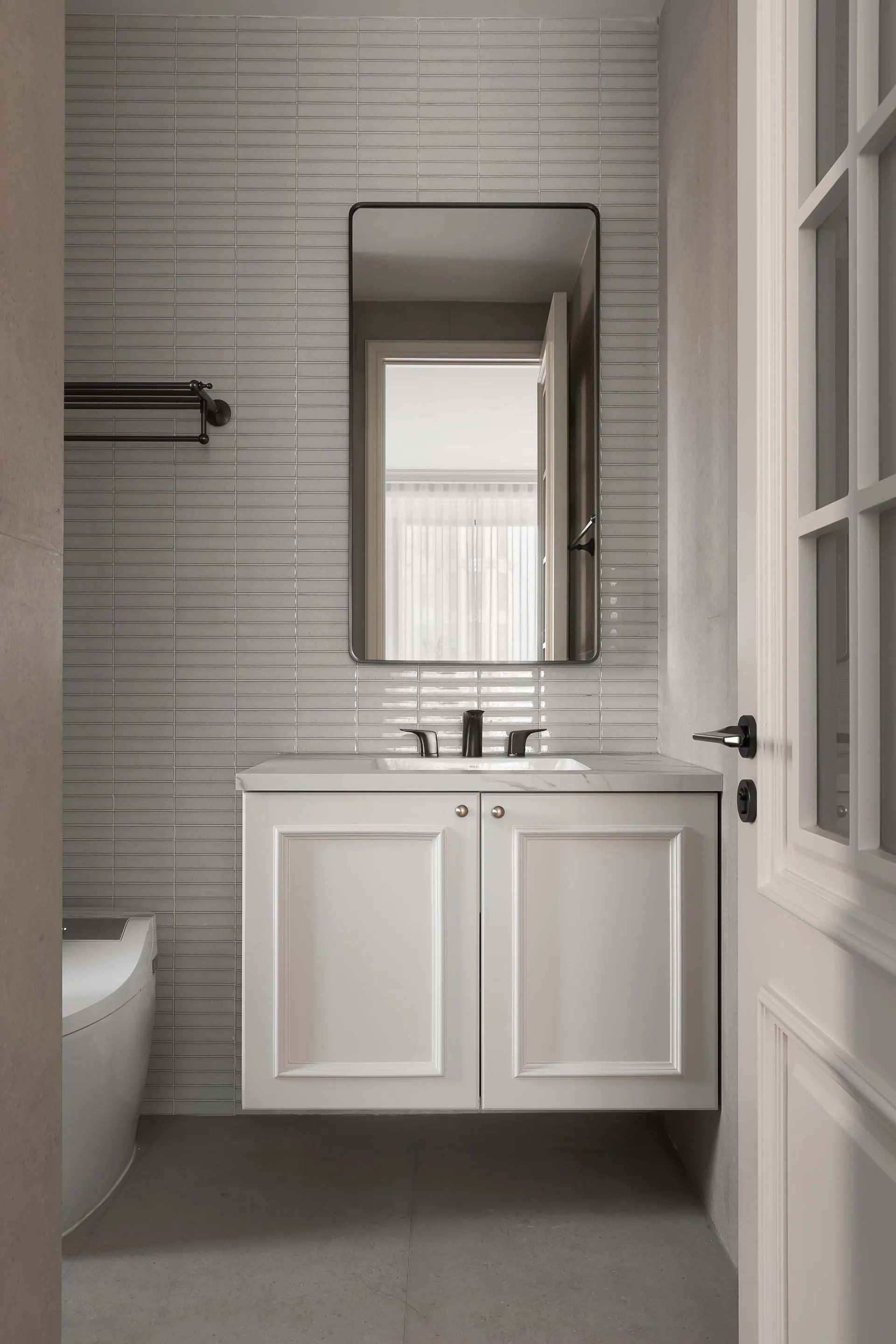 Modern bathroom with concrete and marble tiles featuring a floating vanity with a mirror above and a sink with black faucets.