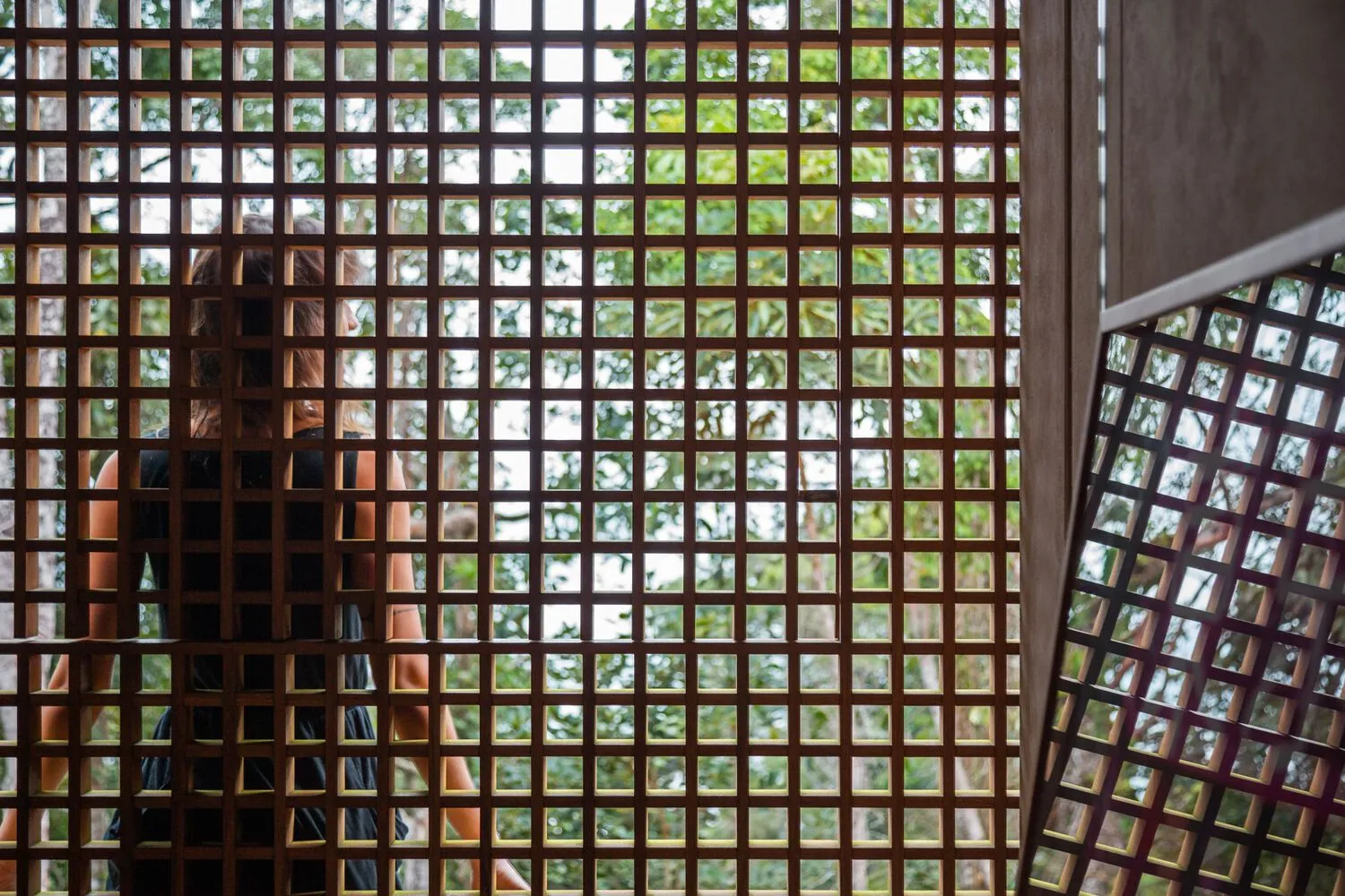 Modern interior design featuring a wooden grid panel with a grid of small, square openings allowing light to filter through.