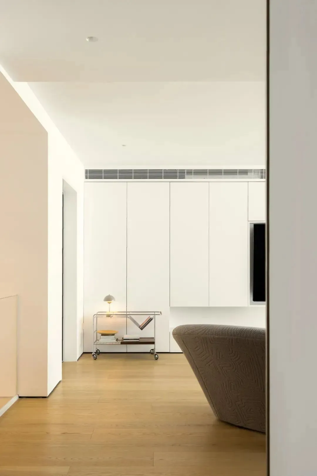 A minimalist living room with a modern design, featuring a wooden floor and simple furniture.