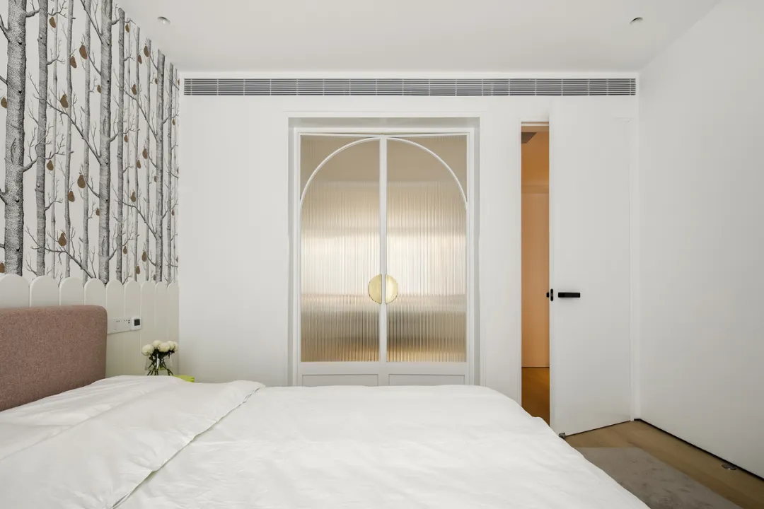 A serene minimalist bedroom with a white ceiling and a bed with a white comforter.