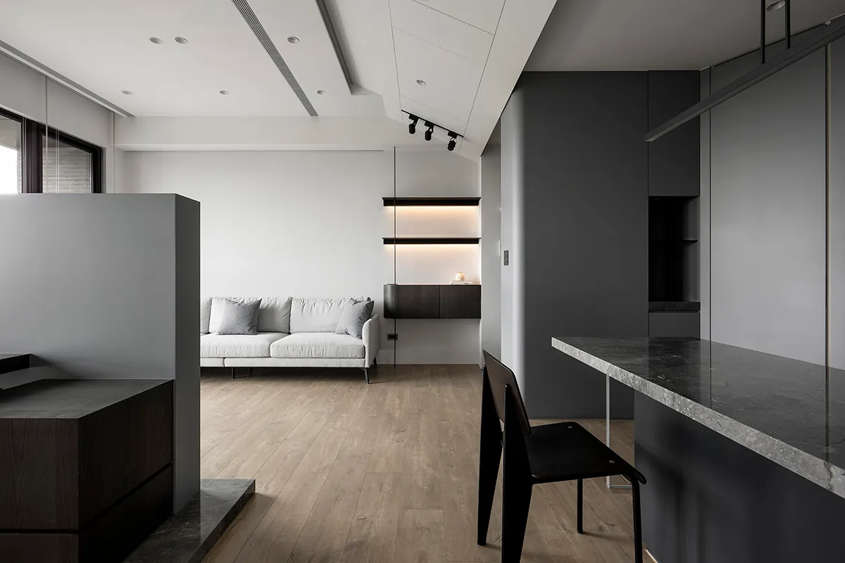 A minimalist living room featuring a concrete floor and wooden furniture.