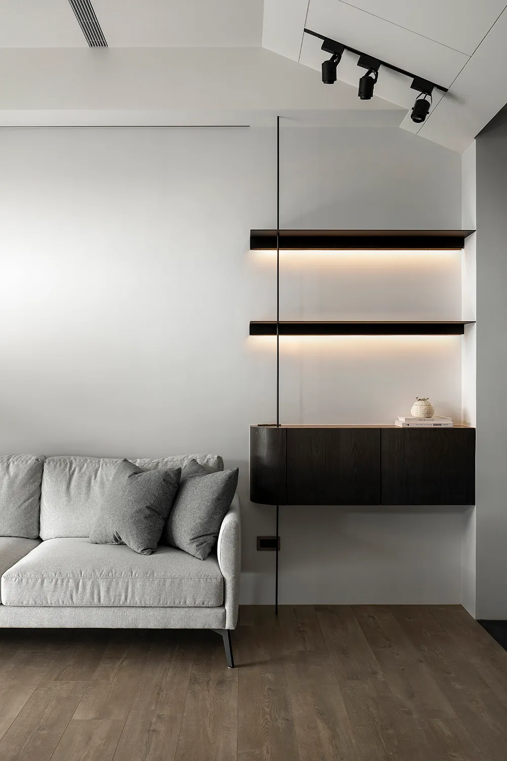 Modern living room with a white sofa, black shelves, and wooden flooring.